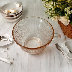Vintage pink depression glass set featuring 2 delicate cups from the American Sweetheart collection and 2 square saucers from the Madrid collection, both adorned with intricate floral and geometric etched patterns. A timeless and sustainable addition to any table or décor.