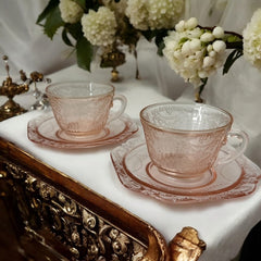 Vintage pink depression glass set featuring 2 delicate cups from the American Sweetheart collection and 2 square saucers from the Madrid collection, both adorned with intricate floral and geometric etched patterns. A timeless and sustainable addition to any table or décor.