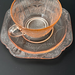 Vintage pink depression glass set featuring 2 delicate cups from the American Sweetheart collection and 2 square saucers from the Madrid collection, both adorned with intricate floral and geometric etched patterns. A timeless and sustainable addition to any table or décor.
