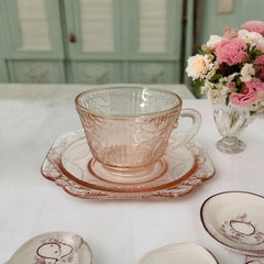 Vintage pink depression glass set featuring 2 delicate cups from the American Sweetheart collection and 2 square saucers from the Madrid collection, both adorned with intricate floral and geometric etched patterns. A timeless and sustainable addition to any table or décor.