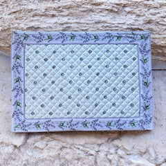 Reversible quilted cotton placemat in Lauris Light Yellow by Marat d’Avignon, featuring a white center with lavender purple floral medallions and a border of lavender sprigs and olive branches, with a white reverse side  scattered with tiny lavender  blossoms, crafted in Provence.