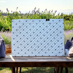 Reversible quilted cotton placemat in Lauris Light Yellow by Marat d’Avignon, featuring a white center with lavender purple floral medallions and a border of lavender sprigs and olive branches, with a white reverse side  scattered with tiny lavender  blossoms, crafted in Provence.