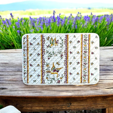 Provence Reversible quilted cotton placemat in Moustiers Red by Tissus Toselli, featuring traditional Provençal motifs inspired by Moustiers ceramics, with two birds in flight, floral garlands, and cream trim.