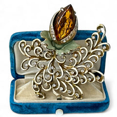Vintage H. Pomerantz floral brooch featuring a large topaz-colored marquise rhinestone set in gold-tone metal, accented with green and cream enamel leaves and clear rhinestones; signed on the reverse, circa 1940s, measuring 3 inches by 3 inches.