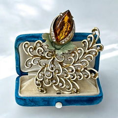 Vintage H. Pomerantz floral brooch featuring a large topaz-colored marquise rhinestone set in gold-tone metal, accented with green and cream enamel leaves and clear rhinestones; signed on the reverse, circa 1940s, measuring 3 inches by 3 inches.