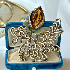 Vintage H. Pomerantz floral brooch featuring a large topaz-colored marquise rhinestone set in gold-tone metal, accented with green and cream enamel leaves and clear rhinestones; signed on the reverse, circa 1940s, measuring 3 inches by 3 inches.