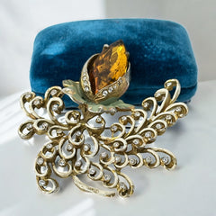 Vintage H. Pomerantz floral brooch featuring a large topaz-colored marquise rhinestone set in gold-tone metal, accented with green and cream enamel leaves and clear rhinestones; signed on the reverse, circa 1940s, measuring 3 inches by 3 inches.