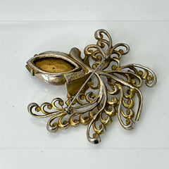 Vintage H. Pomerantz floral brooch featuring a large topaz-colored marquise rhinestone set in gold-tone metal, accented with green and cream enamel leaves and clear rhinestones; signed on the reverse, circa 1940s, measuring 3 inches by 3 inches.