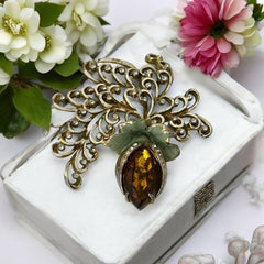 Vintage H. Pomerantz floral brooch featuring a large topaz-colored marquise rhinestone set in gold-tone metal, accented with green and cream enamel leaves and clear rhinestones; signed on the reverse, circa 1940s, measuring 3 inches by 3 inches.