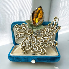 Vintage H. Pomerantz floral brooch featuring a large topaz-colored marquise rhinestone set in gold-tone metal, accented with green and cream enamel leaves and clear rhinestones; signed on the reverse, circa 1940s, measuring 3 inches by 3 inches.