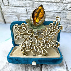 Vintage H. Pomerantz floral brooch featuring a large topaz-colored marquise rhinestone set in gold-tone metal, accented with green and cream enamel leaves and clear rhinestones; signed on the reverse, circa 1940s, measuring 3 inches by 3 inches.