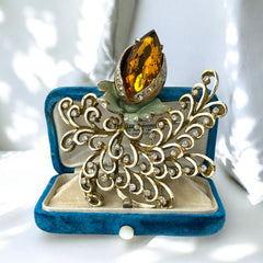 Vintage H. Pomerantz floral brooch featuring a large topaz-colored marquise rhinestone set in gold-tone metal, accented with green and cream enamel leaves and clear rhinestones; signed on the reverse, circa 1940s, measuring 3 inches by 3 inches.