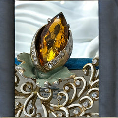 Vintage H. Pomerantz floral brooch featuring a large topaz-colored marquise rhinestone set in gold-tone metal, accented with green and cream enamel leaves and clear rhinestones; signed on the reverse, circa 1940s, measuring 3 inches by 3 inches.