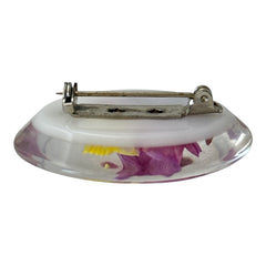 Vintage French reverse carved Lucite brooch featuring a hand-painted pink and yellow orchid on a white background. Oval shape with dimensional floral detail, excellent condition, circa 1950s.