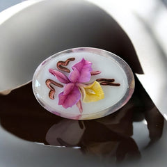 Vintage French reverse carved Lucite brooch featuring a hand-painted pink and yellow orchid on a white background. Oval shape with dimensional floral detail, excellent condition, circa 1950s.