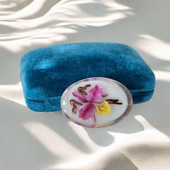 Vintage French reverse carved Lucite brooch featuring a hand-painted pink and yellow orchid on a white background. Oval shape with dimensional floral detail, excellent condition, circa 1950s.