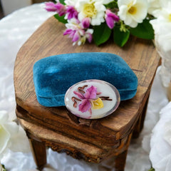 Vintage French reverse carved Lucite brooch featuring a hand-painted pink and yellow orchid on a white background. Oval shape with dimensional floral detail, excellent condition, circa 1950s.