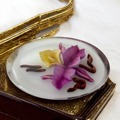Vintage French reverse carved Lucite brooch featuring a hand-painted pink and yellow orchid on a white background. Oval shape with dimensional floral detail, excellent condition, circa 1950s.