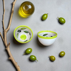 Small round ceramic bowl with green interior and rim, hand-painted with swirling olive branches, black olives, and green leaves on a beige base; measures 4 inches in diameter and 2.5 inches high.