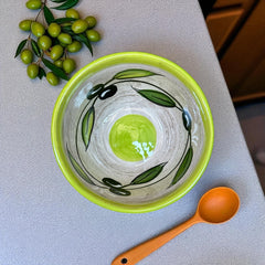 Small round ceramic bowl with green interior and rim, hand-painted with swirling olive branches, black olives, and green leaves on a beige base; measures 4 inches in diameter and 2.5 inches high.