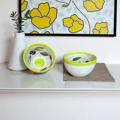Small round ceramic bowl with green interior and rim, hand-painted with swirling olive branches, black olives, and green leaves on a beige base; measures 4 inches in diameter and 2.5 inches high.