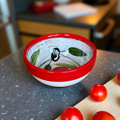 Mini ceramic bowl with red rim and white base, hand-painted with black olives and green leaves; measures 3¾ inches in diameter and 1¾ inches high, ideal for condiments or small servings.