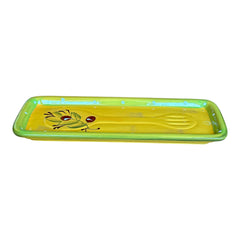 Rectangular ceramic spoon rest with yellow interior and green polka-dot rim, featuring hand-painted olive leaves, red berries, and whimsical fork and spoon motif; measures 11 by 4 inches.