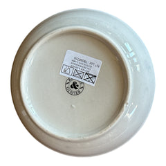 Round ceramic serving dish with red and black rim, hand-painted with green olive branches and brown olives on a cream base, accompanied by two small matching vessels nested inside.