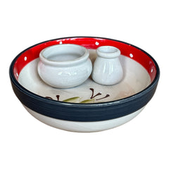 Round ceramic serving dish with red and black rim, hand-painted with green olive branches and brown olives on a cream base, accompanied by two small matching vessels nested inside.