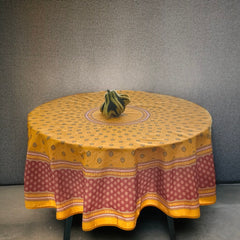 Round coated cotton tablecloth in golden yellow and deep red, featuring concentric Provençal floral and geometric patterns