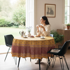Round coated cotton tablecloth in golden yellow and deep red, featuring concentric Provençal floral and geometric patterns