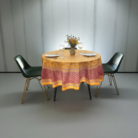 Round coated cotton tablecloth in golden yellow and deep red, featuring concentric Provençal floral and geometric patterns