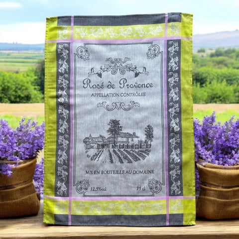French Provence tea towel featuring the Rosé de Provence Appellation Contrôlée design, showcasing a vineyard and winery in elegant cotton. Available in orange with yellow accents and green with soft purple and gray details. Decorative and eco-friendly kitchen decor.