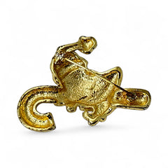 Vintage gold-tone brooch featuring Santa Claus in red and white enamel, riding a striped candy cane with green accent; 1980s/90s holiday design, photographed on neutral background.