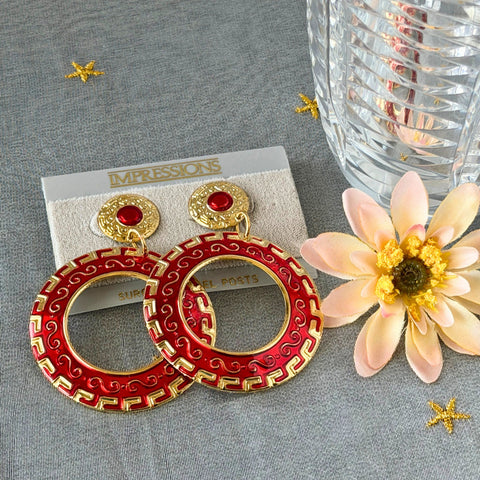 Vintage 1980s red enamel and gold‑tone circle dangle post earrings with pressed scroll and Greek key design on original Impressions card.