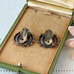 Vintage Renoir copper and black modernist clip‑on earrings with circular bead rim and sculptural center design, signed Renoir.