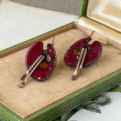 Vintage Matisse Renoir red enamel and copper artist palette earrings with miniature paintbrush design, mid‑century modern clip‑ons from the 1950s–1960s.