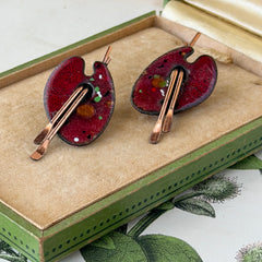 Vintage Matisse Renoir red enamel and copper artist palette earrings with miniature paintbrush design, mid‑century modern clip‑ons from the 1950s–1960s.