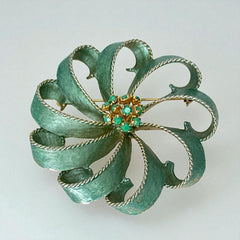 Vintage 1960s floral brooch with light green enamel ribbon petals, gold tone rope edges, and rhinestone center.