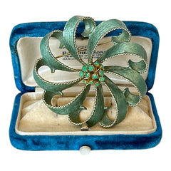 Vintage 1960s floral brooch with light green enamel ribbon petals, gold tone rope edges, and rhinestone center.