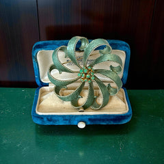 Vintage 1960s floral brooch with light green enamel ribbon petals, gold tone rope edges, and rhinestone center.
