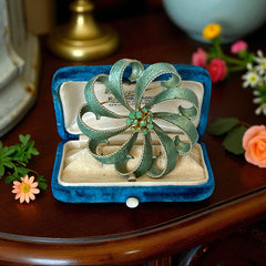 Vintage 1960s floral brooch with light green enamel ribbon petals, gold tone rope edges, and rhinestone center.