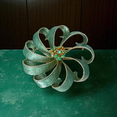 Vintage 1960s floral brooch with light green enamel ribbon petals, gold tone rope edges, and rhinestone center.