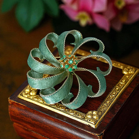 Vintage 1960s floral brooch with light green enamel ribbon petals, gold tone rope edges, and rhinestone center.