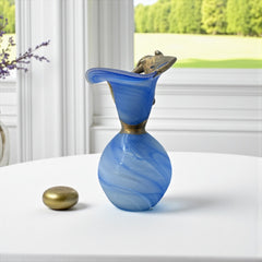 Signed Romanian handblown art glass vase from the 1990s featuring swirling blue glass and sculptural bronze overlay with organic vine-like forms. The vase has a flared top, narrow base, and an undeciphered artist’s signature etched into the glass. A collectible decorative piece in very good vintage condition.