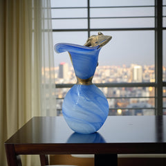 Signed Romanian handblown art glass vase from the 1990s featuring swirling blue glass and sculptural bronze overlay with organic vine-like forms. The vase has a flared top, narrow base, and an undeciphered artist’s signature etched into the glass. A collectible decorative piece in very good vintage condition.