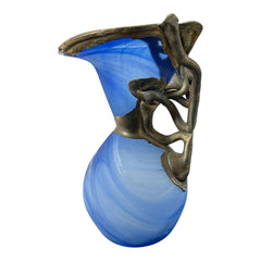 Signed Romanian handblown art glass vase from the 1990s featuring swirling blue glass and sculptural bronze overlay with organic vine-like forms. The vase has a flared top, narrow base, and an undeciphered artist’s signature etched into the glass. A collectible decorative piece in very good vintage condition.