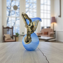Signed Romanian handblown art glass vase from the 1990s featuring swirling blue glass and sculptural bronze overlay with organic vine-like forms. The vase has a flared top, narrow base, and an undeciphered artist’s signature etched into the glass. A collectible decorative piece in very good vintage condition.