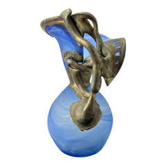 Signed Romanian handblown art glass vase from the 1990s featuring swirling blue glass and sculptural bronze overlay with organic vine-like forms. The vase has a flared top, narrow base, and an undeciphered artist’s signature etched into the glass. A collectible decorative piece in very good vintage condition.