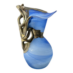 Signed Romanian handblown art glass vase from the 1990s featuring swirling blue glass and sculptural bronze overlay with organic vine-like forms. The vase has a flared top, narrow base, and an undeciphered artist’s signature etched into the glass. A collectible decorative piece in very good vintage condition.
